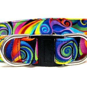May include: A colorful dog collar with a swirling pattern in shades of blue, green, yellow, orange, pink, and red. The collar has a black plastic buckle and silver metal D-rings.