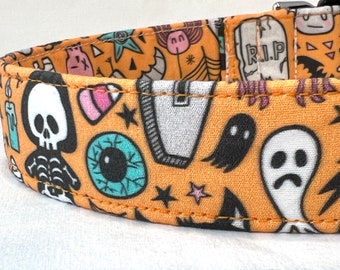 May include: Orange fabric dog collar with a Halloween-themed print featuring ghosts, skulls, eyeballs, and stars. The collar has a stitched seam and the text "R.I.P." is visible.