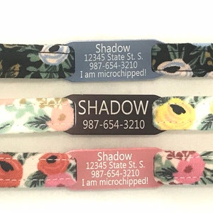 May include: Three dog collar tags with different colored backgrounds. The top tag is blue with white text that reads "Shadow 12345 State St. S. 987-654-3210 I am microchipped!" The middle tag is black with white text that reads "SHADOW 987-654-3210". The bottom tag is pink with white text that reads "Shadow 12345 State St. S. 987-654-3210 I am microchipped!"