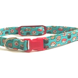 May include: A turquoise blue cat collar with a red buckle and a silver D-ring. The collar is decorated with a repeating pattern of sushi rolls.
