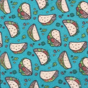 May include: A blue fabric with a repeating pattern of white tacos with green lettuce and brown meat fillings.