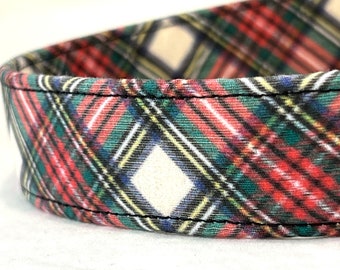 May include: Close-up of a fabric with a classic plaid pattern. The design features a repeating pattern of red, green, yellow, and white lines, creating a traditional tartan look. The fabric is stitched with black thread.