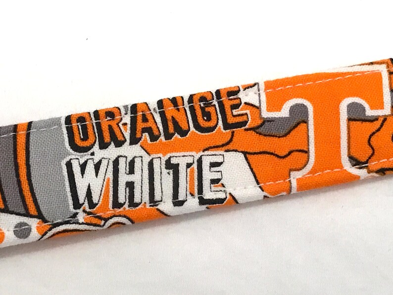 Puede incluir: Tela naranja y blanca con las palabras "ORANGE WHITE" y una "T" estilizada impresa en ella.
