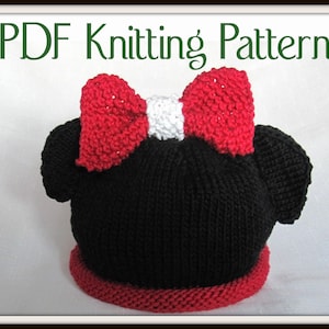 May include: PDF knitting pattern for a black and red knitted hat with a red bow and white centre. The hat has two black ears on the top, resembling a cartoon character.
