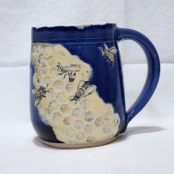Busy bees working on honeycomb on a blue handmade pottery mug