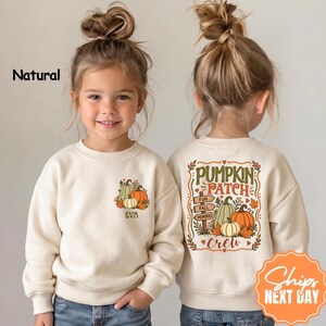 May include: A natural-colored crewneck sweatshirt featuring a small pumpkin graphic and the name EVA on the front left chest, and a large back print with the text PUMPKIN PATCH FUN FALL MEMORIES CREW surrounded by pumpkins and leaves.
