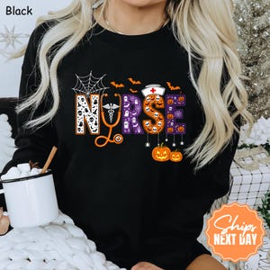 May include: A black long-sleeve sweatshirt featuring the word NURSE in large block letters. The letters are filled with Halloween patterns including ghosts, skulls, and pumpkins. An orange stethoscope forms the letter U, and a nurse cap sits above the R.