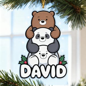 May include: A clear acrylic Christmas ornament featuring three cartoon bears stacked on top of each other. The top bear is brown, the middle bear is white with black accents, and the bottom bear is white. The name "DAVID" is written in white letters at the bottom.