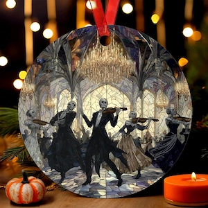 May include: Round Christmas ornament featuring a gothic ballroom scene with skeleton figures playing violins. The artwork has a stained-glass effect with a red ribbon for hanging. A pumpkin and candle are in the foreground.
