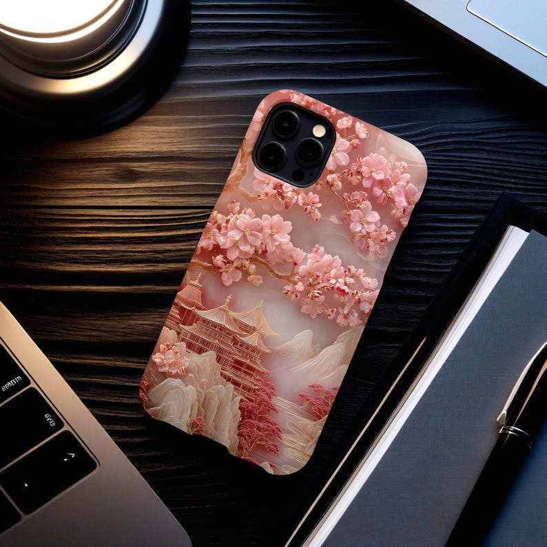 May include: A phone case featuring a 3D relief design of a Japanese pagoda scene with cherry blossoms in shades of pink and white. The case has a marble-like texture and a camera cutout.