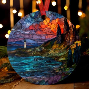 May include: Round ornament featuring a stained-glass style landscape. The design includes a lighthouse, ocean, and mountains under a vibrant sunset sky. A red ribbon is attached for hanging. The ornament is a decorative item.