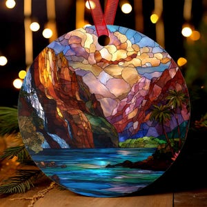 Può includere: Ornamento rotondo con un design a vetrata raffigurante un paesaggio montano con una cascata, un lago e palme. L'ornamento ha un nastro rosso per appenderlo. La tavolozza dei colori comprende sfumature di blu, arancione, marrone e verde.