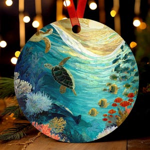 May include: Round ornament featuring an underwater scene with sea turtles, fish, and coral. The design includes a mosaic-style sun and a red ribbon for hanging. The color palette includes shades of blue, green, yellow, and orange.