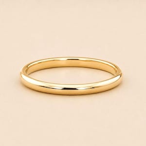 Op de afbeelding: Een gepolijste geelgouden bandring met een glad, afgerond oppervlak en een hoogglans afwerking. De ring heeft een eenvoudig, doorlopend cirkelvormig ontwerp met een constante breedte, waardoor het licht gelijkmatig over het oppervlak weerkaatst.