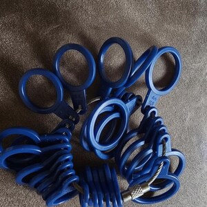 May include: A set of blue ring sizers, connected by a metal cable. The ring sizers are made of plastic and have a loop design. The set includes various sizes for accurate ring measurements. The background is a neutral brown.