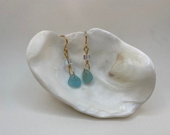 May include: A pair of gold earrings with light blue sea glass and clear crystal accents.