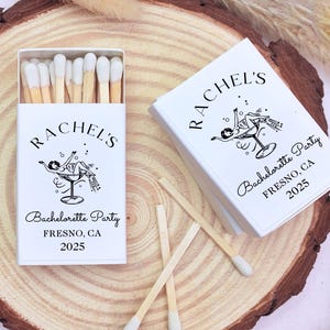 May include: White matchbox with a black and white illustration of a woman in a martini glass. The text on the matchbox reads "Rachel's Bachelorette Party Fresno, CA 2025".