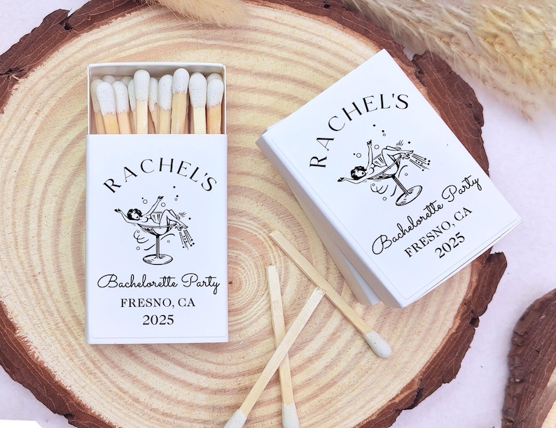 May include: White matchbox with a black and white illustration of a woman in a martini glass. The text on the matchbox reads "Rachel's Bachelorette Party Fresno, CA 2025".
