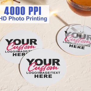 Puede incluir: Posavasos redondos blancos con el texto "YOUR Custom LOGO/IMAGE/TEXT HERE" en negro y rosa. La imagen también incluye una copa de vino y una pera. El texto "4000 PPI HD Photo Printing" está en la parte superior.