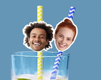 Puede incluir: Un vaso transparente lleno de una bebida, con dos pajitas de papel. Una es de rayas amarillas y blancas, la otra de rayas azules y blancas. La imagen incluye dos caras sonrientes, una con pelo oscuro y otra pelirroja.
