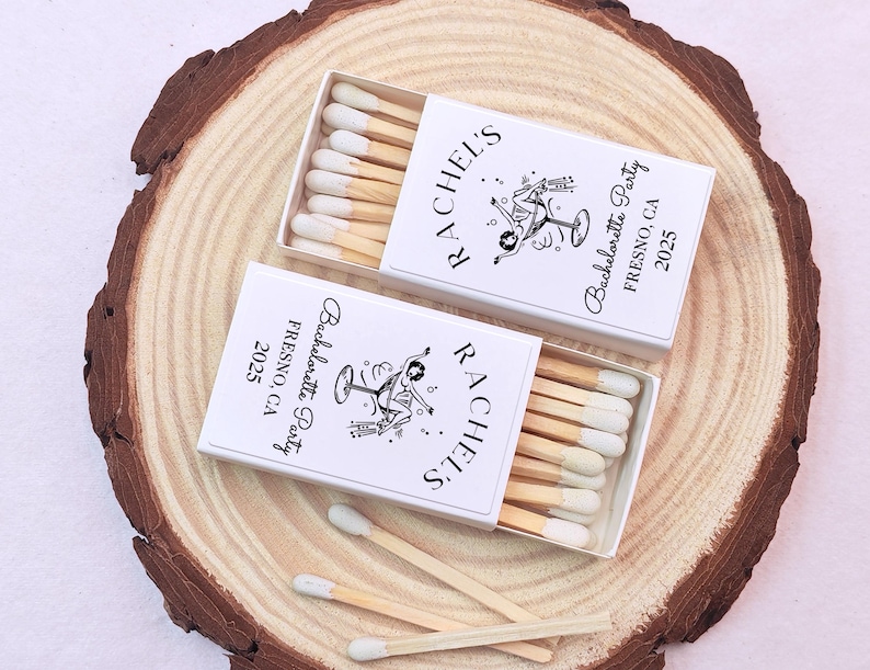 May include: Two white matchboxes with black text and a graphic of a woman holding a martini glass. The text on the boxes reads "Rachel's Bachelorette Party Fresno, CA 2025".