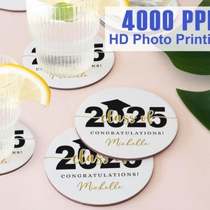 Könnte beinhalten: Weiße runde Untersetzer mit schwarzem Text, der "Class of 2025" in einer goldenen Schriftart sagt. Der Text "Congratulations! Michelle" ist unter dem Jahr gedruckt.