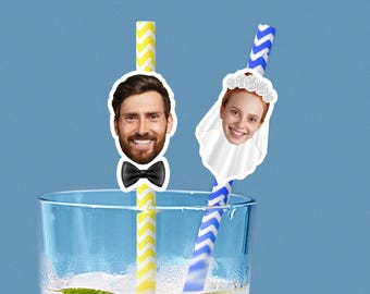 Puede incluir: Un vaso de líquido transparente con dos pajitas. Una pajita es amarilla y blanca con la cara sonriente de un hombre y una pajarita negra. La otra pajita es azul y blanca con la cara sonriente de una mujer con velo y corona floral.