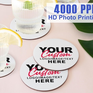 May include: White round coasters with black text that says "YOUR Custom LOGO/IMAGE/TEXT HERE". The coasters are on a pink surface with a glass of lemonade and a green leaf.