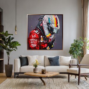 May include: A framed painting of a racing helmet and suit. The helmet is white, black, and yellow with a rainbow stripe. The suit is red with white text and logos. The artwork is displayed in a living room setting.