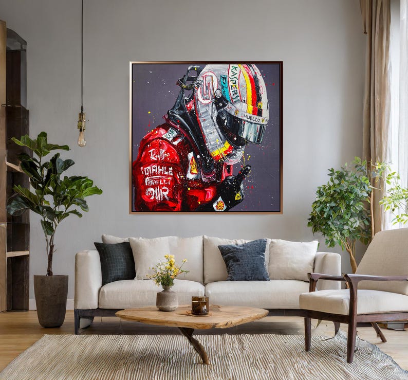 May include: A framed painting of a racing helmet and suit. The helmet is white, black, and yellow with a rainbow stripe. The suit is red with white text and logos. The artwork is displayed in a living room setting.