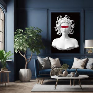 May include: A white Medusa bust with a red stripe across the eyes is displayed on a black background. The artwork is mounted on a dark blue wall above a blue sofa with decorative cushions. A potted plant and a side table are in the foreground.