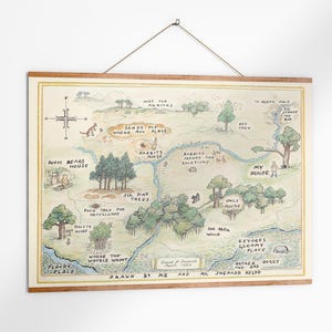 May include: A framed map illustration of a whimsical landscape with text labels like "Pooh Bear's House" and "Sandy Pit Where Pooh Plays." The map is in soft watercolor tones, with a wooden frame and a hanging string.