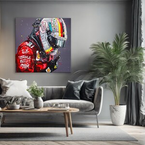 May include: A square canvas art print featuring a portrait of a racing driver in a helmet and red racing suit. The helmet is silver with a rainbow stripe and the suit has sponsor logos. The artwork is set against a gray background.
