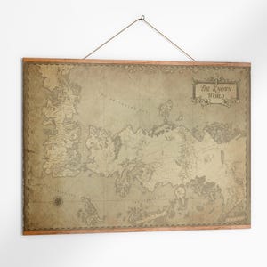 May include: A vintage-style map print of "The Known World" with a wooden frame, hanging from a string. The map features detailed illustrations of continents and islands in shades of brown and beige, creating a classic aesthetic.
