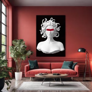 May include: A white Medusa bust with a red band across the eyes, set against a black backdrop. The artwork is displayed in a living room with a red sofa, green cushions, and a round wooden coffee table. The room has a modern design.