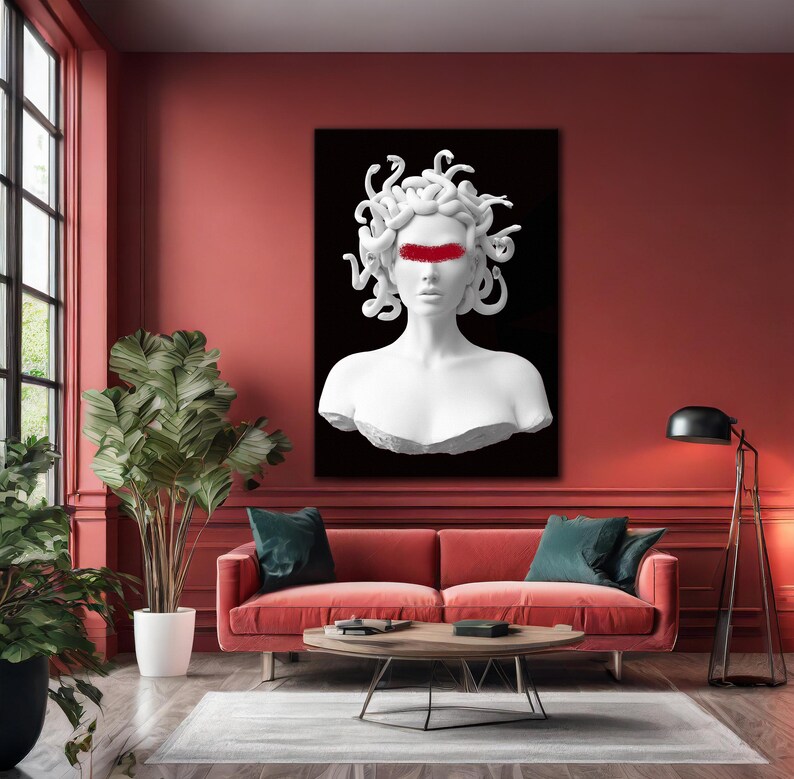 May include: A white Medusa bust with a red band across the eyes, set against a black backdrop. The artwork is displayed in a living room with a red sofa, green cushions, and a round wooden coffee table. The room has a modern design.