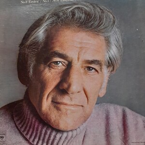 May include: Album cover featuring a portrait of Leonard Bernstein in a pink turtleneck sweater. The album title reads "Bernstein conducts Four Great Beethoven Symphonies" with the New York Philharmonic listed. The cover is a vintage record.