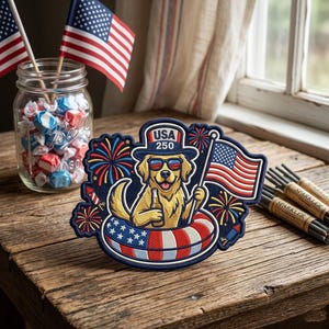 May include: Embroidered patch featuring a golden retriever wearing sunglasses and a hat that says "USA 250". The dog is holding a beer and an American flag, floating in a red, white, and blue inner tube. Fireworks and a jar of candy are in the background.