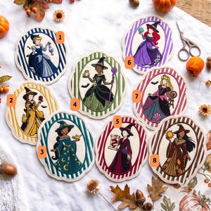 May include: Eight embroidered fabric patches featuring stylized figures in witch hats and gowns, each framed by a scalloped border with vertical stripes. The patches are numbered one through eight and display various magical items like potions, frogs, and scrolls.