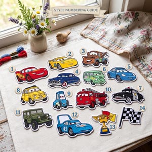 Op de afbeelding: Een verzameling van veertien geborduurde patches met cartoonvoertuigen en race-iconen uit de Cars-filmreeks, elk voorzien van een genummerd rond label. De set bevat Lightning McQueen, Takel, een brandweerwagen en een trofee.