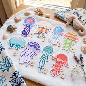 May include: Eight embroidered jellyfish patches arranged on a white fabric surface. Each patch features a unique color scheme, including pink, orange, blue, green, and purple, with numbered tags from 1 to 8 placed next to each individual design.