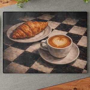 May include: A cutting board featuring a still life of breakfast items. A flaky croissant sits on a white plate, next to a cup of coffee with heart-shaped latte art. The background has a black and white checkered pattern.