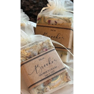 custom soap favors with gold mica top swirl and optional dried botanicals, in ivory organza bags with rustic personalized kraft labels