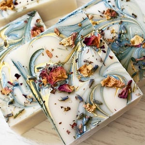Custom designed soap favors with a dusty blue and gold mica swirl top and dried botanicals