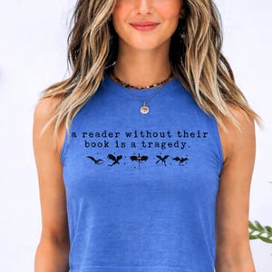 May include: A blue crop top with the text "a reader without their book is a tragedy." and four black silhouette images. The shirt is a heather true royal color.