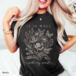 May include: Black t-shirt with a floral and butterfly design and the text "IT IS WELL with my soul" in white. A comfortable, casual style.