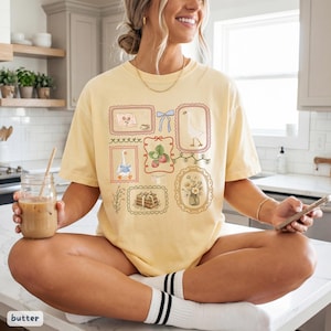May include: A white ceramic mug with a black handle and the text "But First, Coffee" in a bold, black font. The mug is set against a blurred background, suggesting a cozy setting.