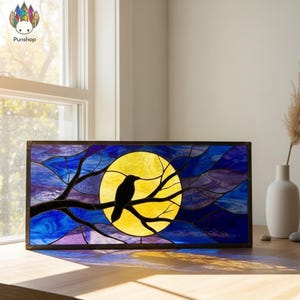 Puede incluir: Panel de vidrieras con un cuervo negro posado en una rama frente a una luna amarilla. El fondo tiene tonos azules y morados. El panel está enmarcado en un borde marrón oscuro.
