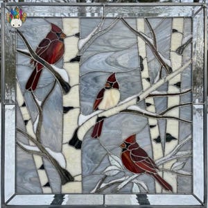May include: A square stained glass panel featuring three red cardinals perched on branches among white birch trees. The glass uses shades of red, white, gray, and cream with dark lead lines. The scene depicts a winter forest setting.