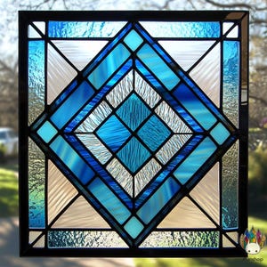 May include: A stained glass window with a geometric design featuring a large diamond shape made up of smaller blue and white squares. The window is framed in black.